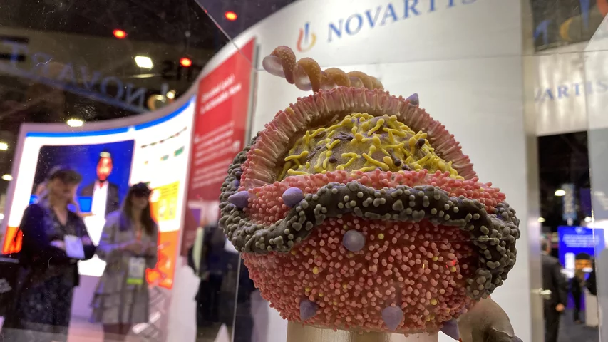 A cellular model in the Novartis booth promoting inclisiran (Leqvio) and attendees watching an augmented reality presentation in thye background. ACC23 DF 1
