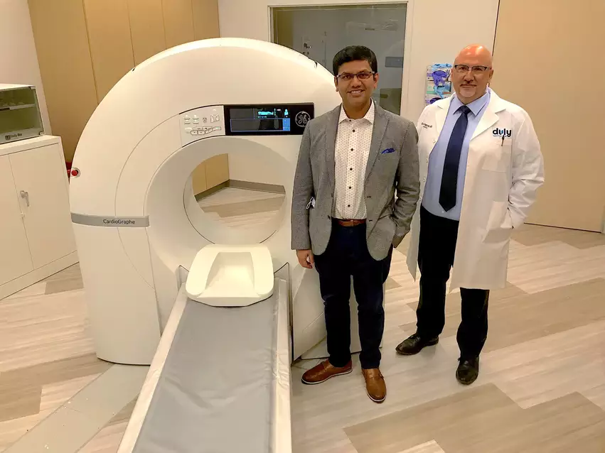 Cardiac imager Sujith Kalathiveetil, MD, and Evans Pappas, MD, director of cardiology, with their compact dedicated cardiac CT scanner at a Duly Health and Care outpatient clinic in Lisle, Illinois. It was one of the first installations of a dedicated cardiac CT scanner at an outpatient center since the adoption of the 2021 chest pain guidelines. Photo by Dave Fornell 
