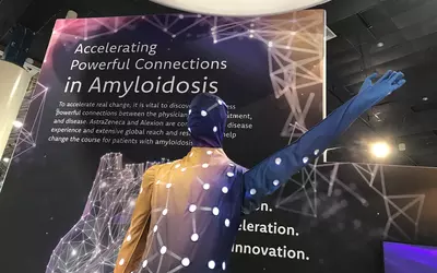Amyloidosis man waving hello to attendees from AstraZeneca booth at ACC.23. Imaging volumes for amyloidosis have increased in recent years now that there is a treatment for the condition. #ACC #ACC23 #Amyloidosis