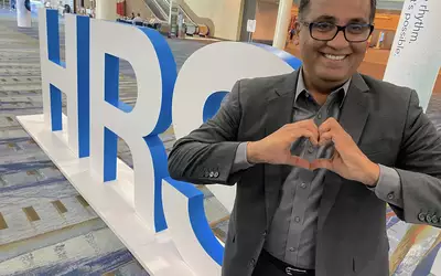 Electrophysiologist DJ Lakkireddy poses in front of the Heart Rhythm Society logo at the 2023 meeting. Photo by dave Fornell