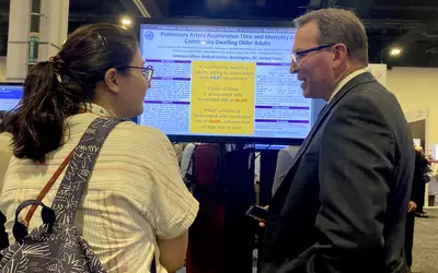 Attendee and researcher discussing posters on the expo floor at ASE 2023.