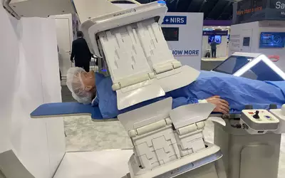 The Radiaction radiation protection system displayed at TCT 2023.  It uses leafs of extendable radiation blocking material on both the X-ray source and detector of the angiographic C-arm. The system will deploy and has sensors to stop before touching the patient or table. The shields fold back to move the C-arm or enable better patient access. Photo by Dave Fornell